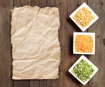 Legumes in bowls and craft paper on a wooden table