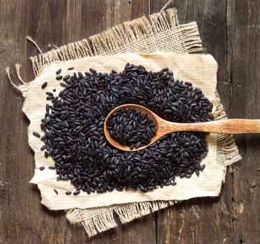 Black rice with a spoon on a wooden table