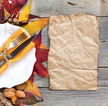Autumn table setting with leaves, nuts, acorns and paper