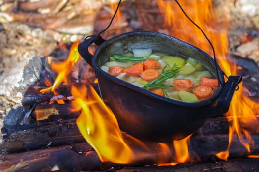 vegetable soup in old tourist pot at fire place Summer trekking activity
