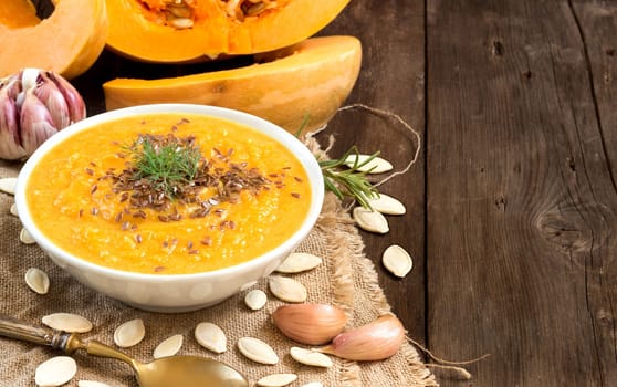Fresh tomatoe soup with vegetables and spoon on a wooden table