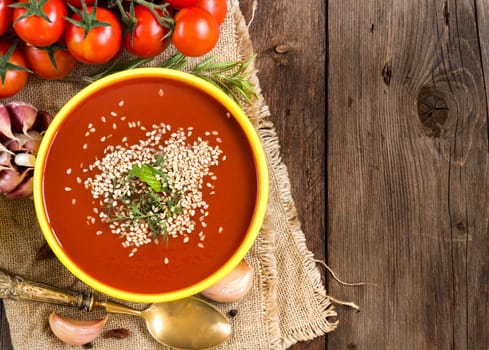 Fresh tomatoe soup with vegetables on a wooden table