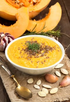 Fresh pumpkin soup with a spoon on a wooden table