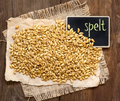 Raw organic spelt and small chalkboard on a wooden table