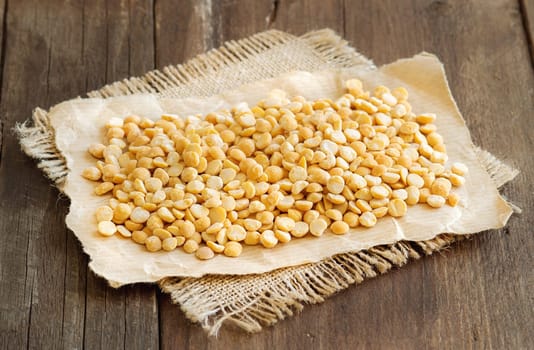 Yellow peas on a paper and burlap on a wooden table
