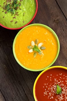 Tomatoe, pumpkin and green peas soups on a wooden table