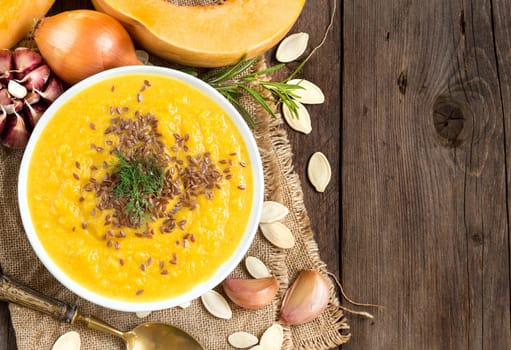 Fresh pumpkin soup with a spoon on a wooden table