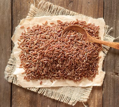 Red rice on burlap and paper with a spoon