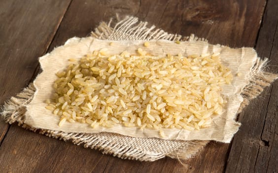 Unpolished rice on paper and burlap on a wooden table