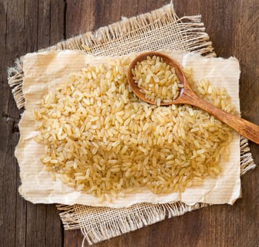 Unpolished rice with a spoon on a wooden table