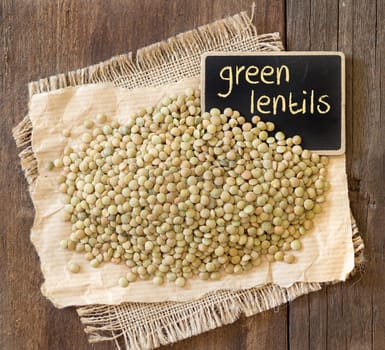 Green lentils on wooden table with small chalkboard