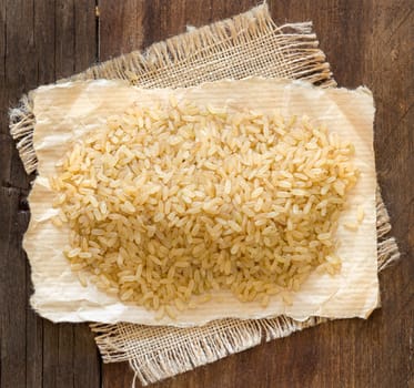 Unpolished rice on paper and burlap on a wooden table