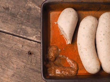 Delicious Bavarian white sausages with sweet mustard in a rustic ceramic bowl