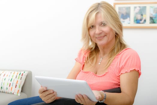 a beautiful mature woman using electronic tablet at home