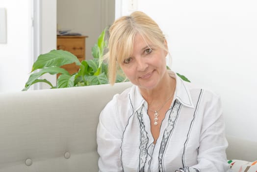 Portrait of blond mature woman relaxing in sofa