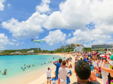 Philipsburg, Sint Maarten, Netherlands - May 14, 2016: The beach at Maho Bay is one of the world's premier planespotting destinations. Airplanes landing at the Princess Juliana Airport fly over beachgoers.