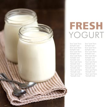 Jars of fresh natural yogurt with spoons on wooden background