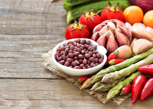 Azuki beans in a bowl and vegetables on wooden table