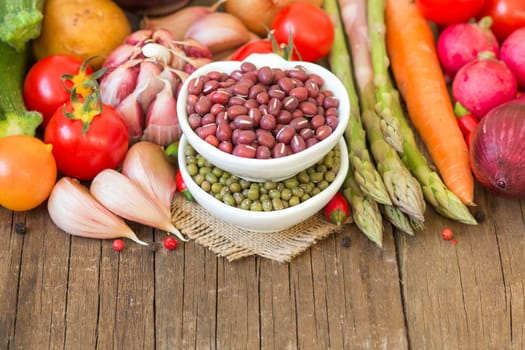 Mung and azuki beans in a bowl and vegetables on wooden table