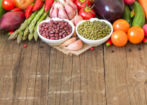 Mung and azuki beans in a bowl and vegetables on wooden table
