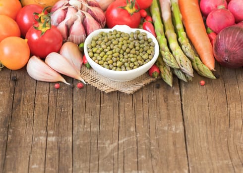 Mung beans in a bowl and vegetables on wooden table