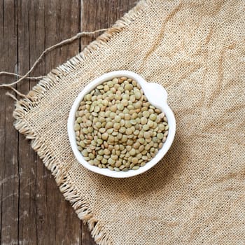 Green lentils in a bowl on burlap
