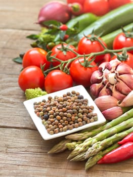 Raw organic roveja beans and vegetables on wooden table