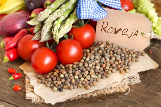 Raw organic roveja beans and vegetables on wooden table