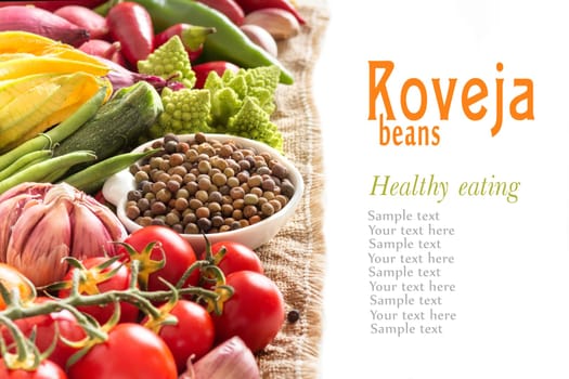 Raw organic roveja beans and vegetables isolated on white