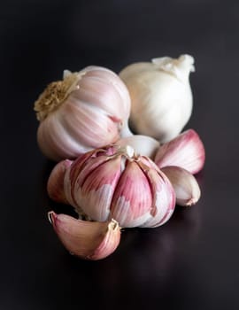 Whole and split fresh garlic on a black table