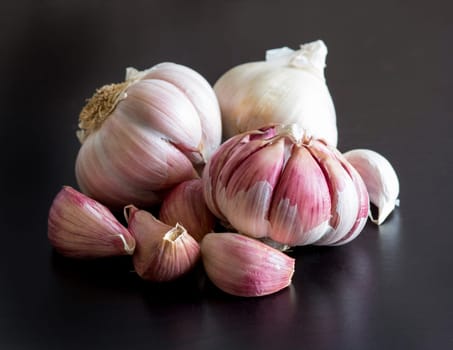 Whole and split fresh garlic on a black table