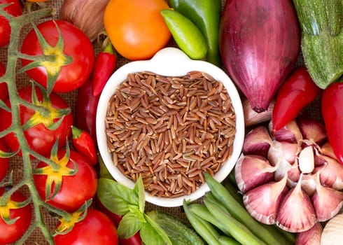 Red organic rice in bowl and vegetables