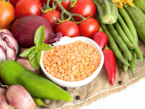 Red lentils in bowl and vegetables isolated on white
