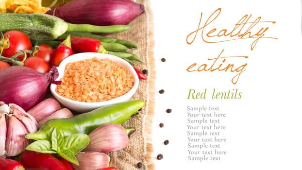 Red lentils in bowl and vegetables isolated on white