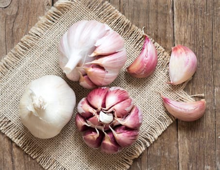 Whole and split fresh garlic on wooden background