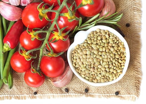 Green lentils in bowl and vegetables isolated on white