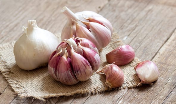 Whole and split fresh garlic on wooden background