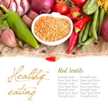 Red lentils in bowl and vegetables isolated on white
