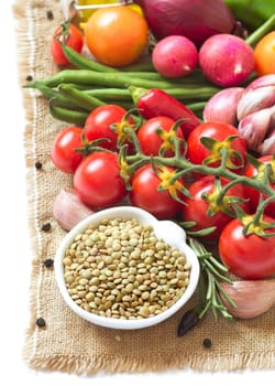 Green lentils in bowl and vegetables isolated on white