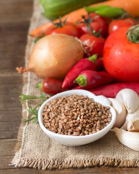 Raw Organic buckwheat and vegetables on wooden table