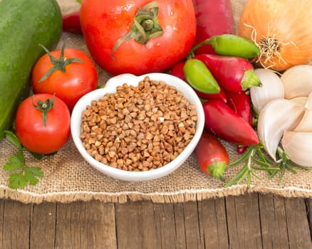 Raw Organic buckwheat and vegetables on wooden table