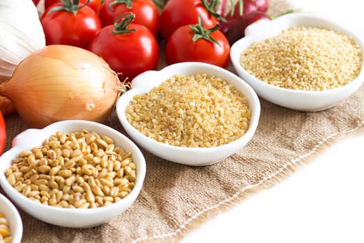 Millet, spelt, bulgur and vegetables on wooden table