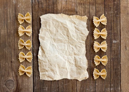 Pasta and paper on old wooden table