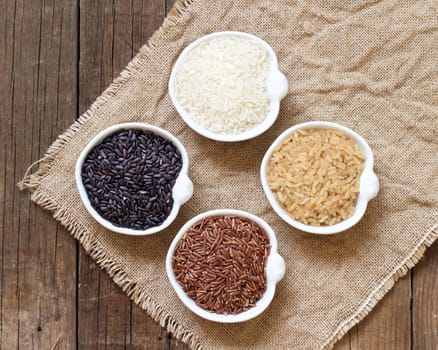 Variety of rice in bowls on wooden table