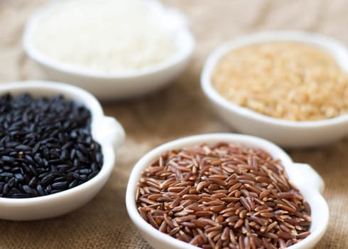 Variety of rice in bowls on wooden table