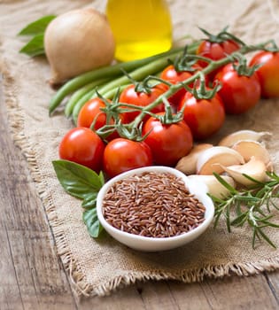 Red organic rice, olive oil, vegetables and herbs on wooden background