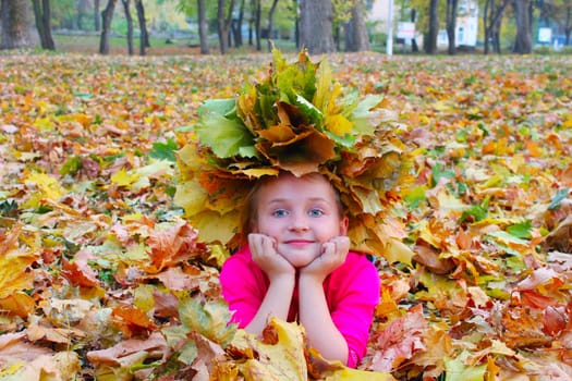 girl with a wreath of yellow leaves lying on the yellow leaves