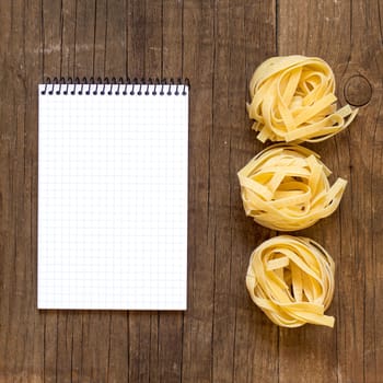 Pasta and notebook on old wooden table