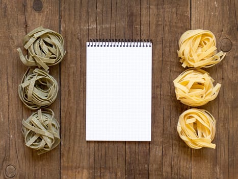 Pasta and notebook on old wooden table