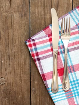 Fork and knife on kitchen towel and old wooden table